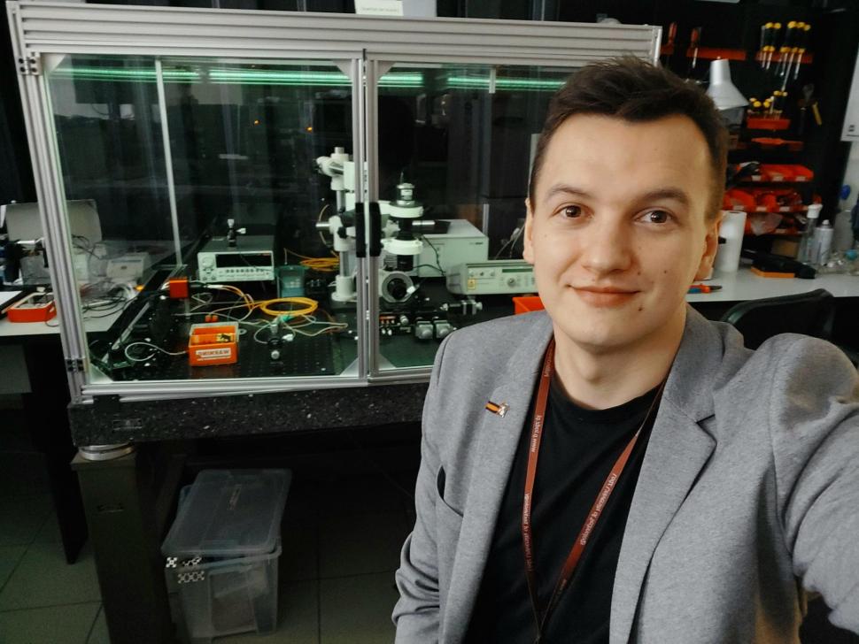 Zdjęcie naukowca na tle światłowodowej aparatury badawczej.